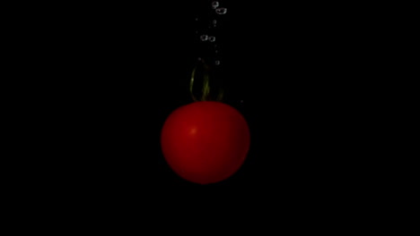 Tomaten-Fallen-Ins-Wasser-Auf-Schwarzem-Hintergrund