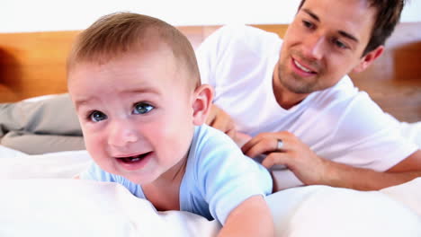 Happy-father-tickling-his-baby-son-on-bed