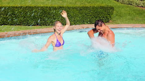 Happy-couple-splashing-each-other-in-the-swimming-pool