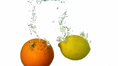 Naranja-Y-Limón-Sumergiéndose-En-Agua-Sobre-Fondo-Blanco.