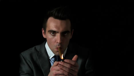 Businessman-lighting-his-cigar-on-black-background