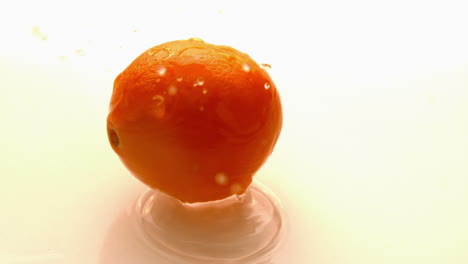 Orange-falling-and-bouncing-on-white-wet-surface