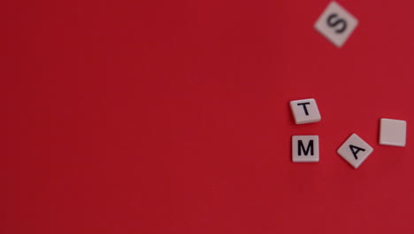 White-letter-tiles-moving-to-spell-out-happy-christmas-on-red-background