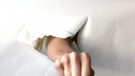 Hand-punching-through-white-paper