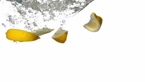 Lemon-segments-plunging-into-water-on-white-background