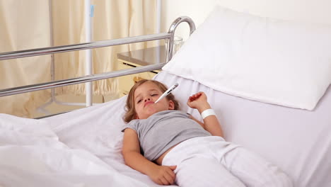 Little-girl-lying-in-hospital-bed-with-a-thermometer