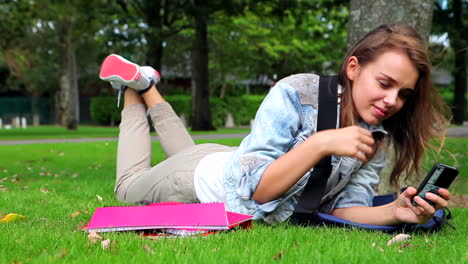 Tired-student-lying-on-the-grass-and-answering-her-phone