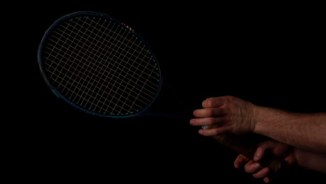 Hand-spinning-a-tennis-racket-on-black-background