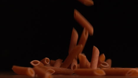 Penne-Nudeln-Gießen-Auf-Schwarzem-Hintergrund