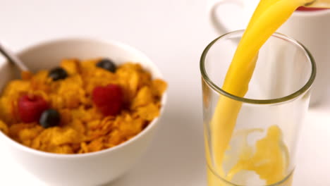 Orange-juice-pouring-into-glass-at-breakfast-table