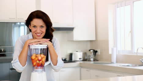 Pretty-brunette-leaning-on-blender-smiling-at-camera