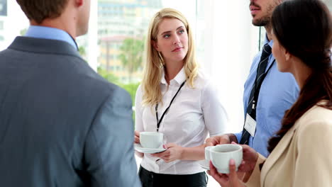 Business-people-standing-at-conference-drinking-coffee