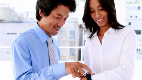 Businesswoman-showing-her-smart-watch-to-colleague