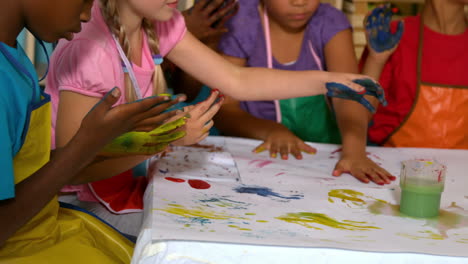 Cute-little-pupils-painting-with-their-hands-in-classroom