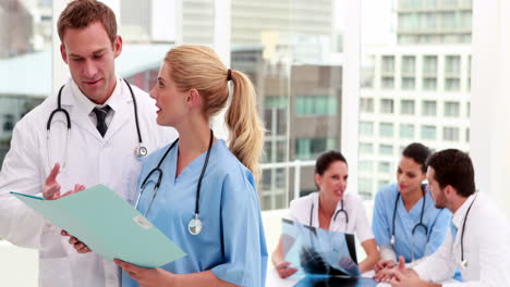 Medical-team-looking-at-file-together-then-smiling-at-camera