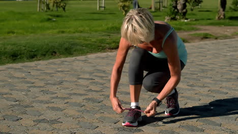 Senior-woman-tying-her-shoelace-on-the-path