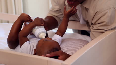 Baby-boy-lying-in-crib-being-fed-by-father