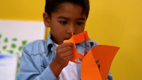 Un-Niño-Lindo-Cortando-Formas-De-Papel-En-El-Aula