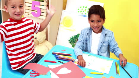 Cute-little-boys-having-art-time-in-the-classroom-waving-to-camera