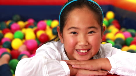 Cute-girl-smiling-at-camera-in-ball-pool