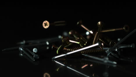 Nails-and-screws-falling-on-black-surface
