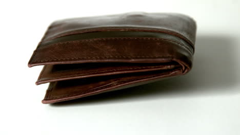 Brown-leather-wallet-falling-on-white-surface