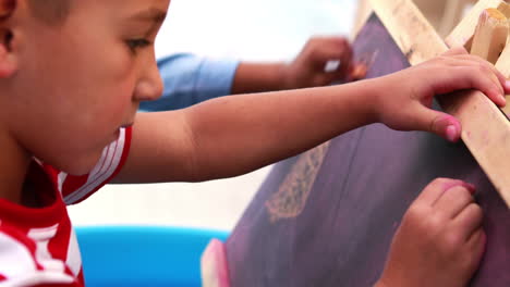 Cute-little-boys-drawing-on-mini-chalkboard