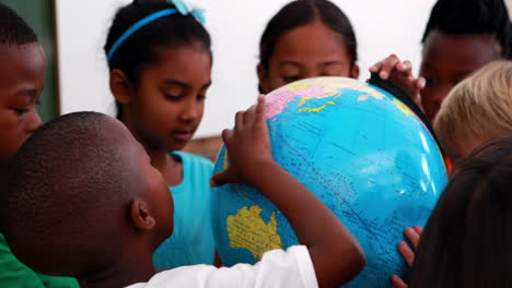 Pupils-looking-at-the-globe-in-classroom