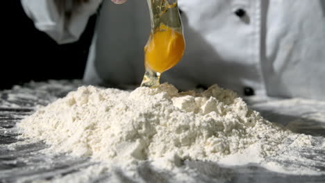 Chef-breaking-egg-over-pile-of-flour