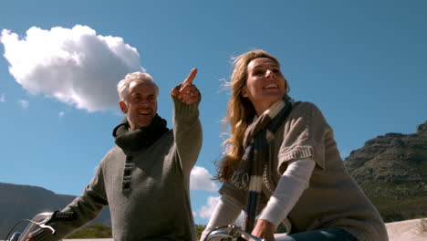 Happy-mature-couple-going-for-bike-ride-on-the-beach