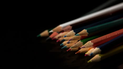 Colour-pencils-falling-on-black-surface