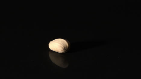 Pistachio-nut-spinning-on-black-surface