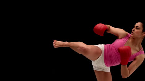 Fit-young-woman-kicking-on-black-background