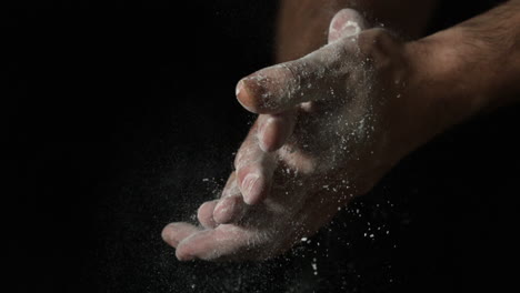 Bakers-hands-rubbing-flour-off-on-black-background