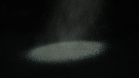 Sand-pouring-on-black-surface