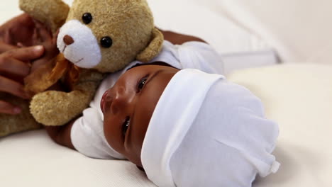 Baby-boy-lying-in-crib-with-teddy-bear