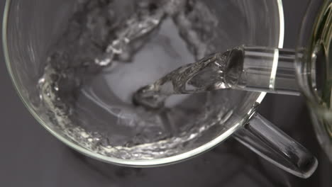 Hot-water-pouring-from-teapot-into-glass-cup