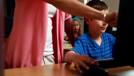 Teacher-helping-little-boy-in-computer-class