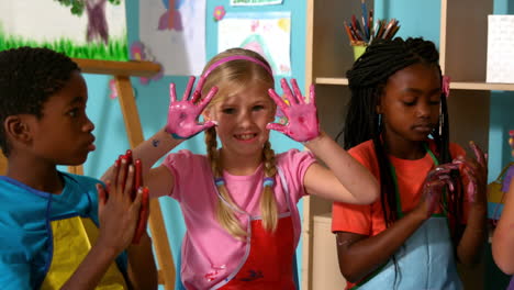 Cute-little-pupils-painting-with-their-hands-in-classroom