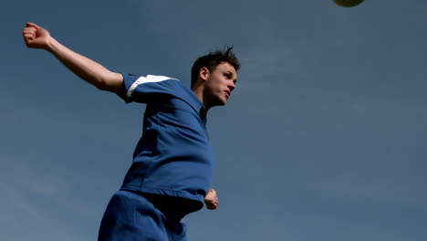 Football-player-heading-the-ball-under-blue-sky