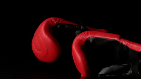 Red-boxing-gloves-falling-on-black-background