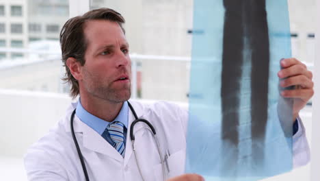 Handsome-doctor-examining-xray-and-smiling-at-camera