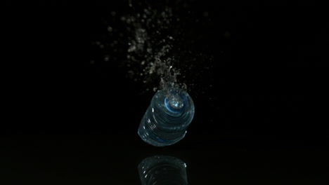 Plastic-bottle-falling-and-spilling-on-black-surface