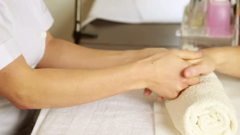 Beauty-therapist-massaging-customers-hands