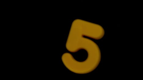 The-number-five-coming-into-focus-on-black-background