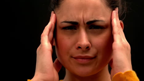 Sick-young-woman-rubbing-her-head-on-black-background