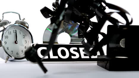 Loose-film-falling-beside-closed-sign-and-videos-and-alarm-clock