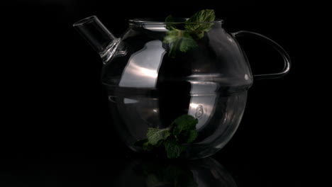 Mint-leaves-falling-into-glass-teapot