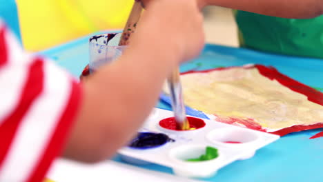 Cute-little-boys-painting-at-table-in-classroom