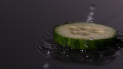 Zucchinischeibe-Fällt-Auf-Nassen-Schwarzen-Hintergrund